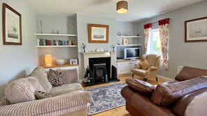 Ein Wohnzimmer mit Kamin, Sofas, einem Fernseher und Bücherregalen.