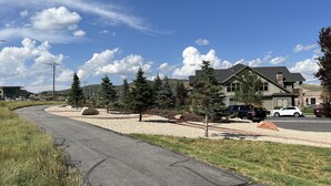 Una calle residencial con una entrada de acceso curva, casas y automóviles estacionados.