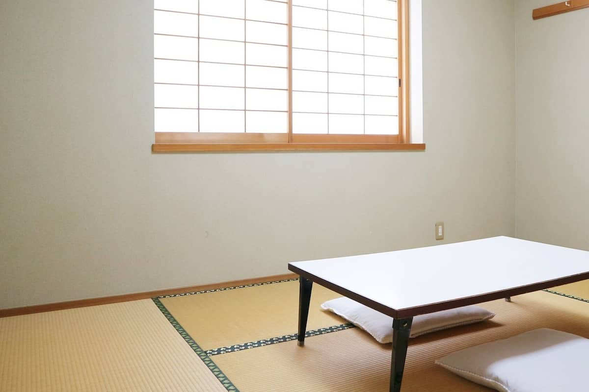 Una habitación con suelo de tatami, una mesa baja y un ventanal de cuadrícula.