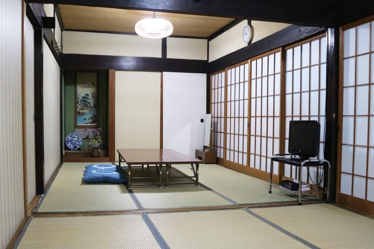Una habitación con esteras de tatami, una mesa baja, un televisor y puertas correderas.