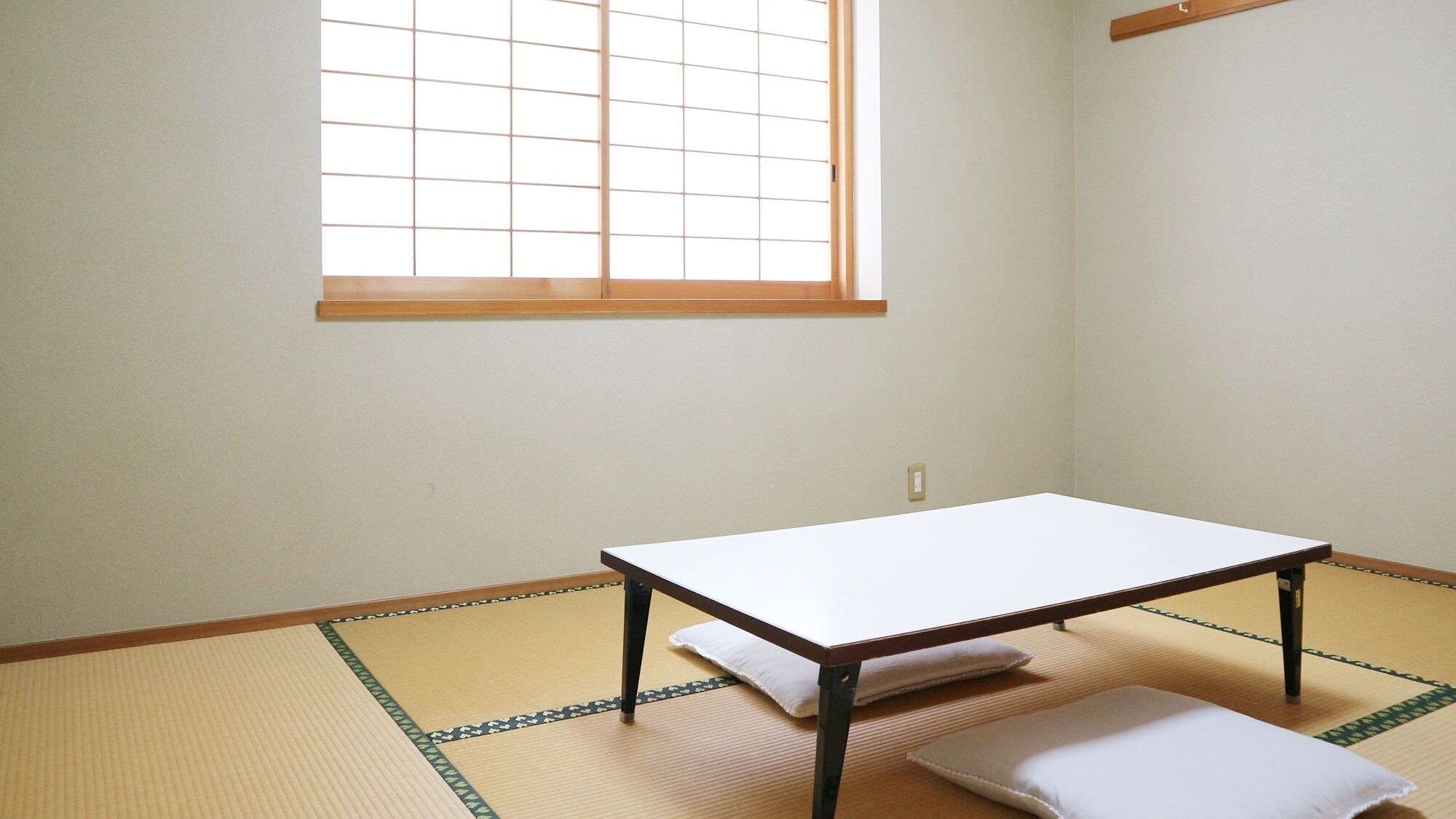 Una habitación con suelo de tatami, una mesa baja y una ventana con diseño de cuadrícula.