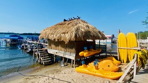 A beachside hut with a thatched roof, a wooden dock, and yellow watercraft. - Walking distance to historic Arnold’s Park and West Lake Okoboji (Arnolds Park)