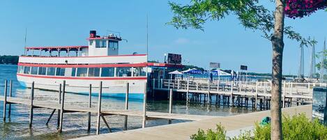 A white boat docked at a pier with a bar sign and a 'Queen' sign on the side.