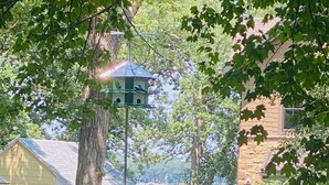 A residential area with a stone house, a yellow building, and a view of a body of water. - Walking distance to historic Arnold’s Park and West Lake Okoboji (Arnolds Park)