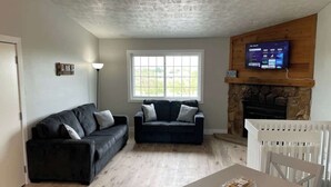Ein Wohnzimmer mit zwei schwarzen Sofas, einem weißen Tisch und einem Kamin.