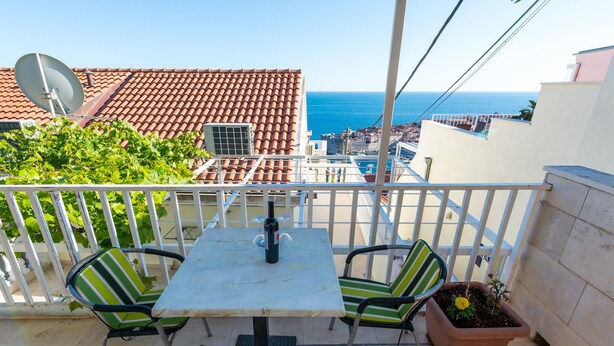 A balcony with a table and chairs, a satellite dish, a potted plant, and a view of the sea. - Guesthouse Home Sweet Home - Standard One-Bedroom Apartment with Balcony (Dubrovnik)