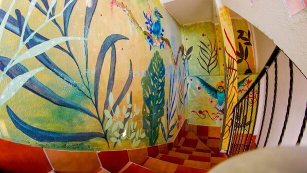Una escalera con arte mural abstracto y colorido y un piso a cuadros.