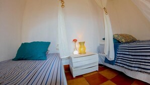 Un dormitorio acogedor con una cama con dosel, una mesita de noche con lámpara y un pequeño atril.