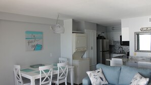 Un espacio habitable compacto con comedor, kitchenette y un sofá azul claro.