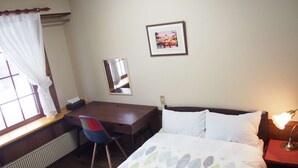 A hotel room with a wooden bed, a desk, a chair, a radiator, a window with curtains, a framed picture on the wall, and a bedside lamp. - Saizu Resort Hotel Urabandai (Kitashiobara)