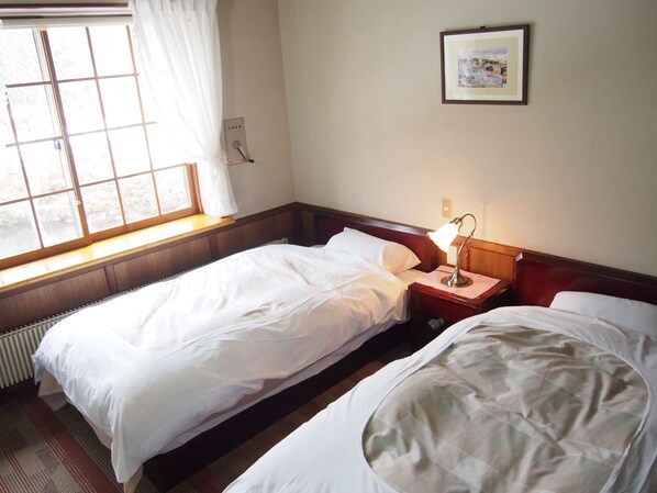 A hotel room with two beds, a window with curtains, a bedside lamp, and a framed picture on the wall. - Saizu Resort Hotel Urabandai (Kitashiobara)