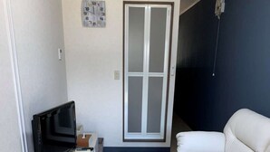 A living room with a white sofa, a television, a small table, and a door with frosted glass panels. - Saizu Resort Hotel Urabandai (Kitashiobara)