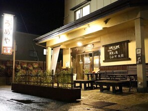 A building with a covered entrance, outdoor seating, and a signboard with Japanese text. - Onogawa Onsen Umeya Ryokan <yamagata> (Yonezawa)