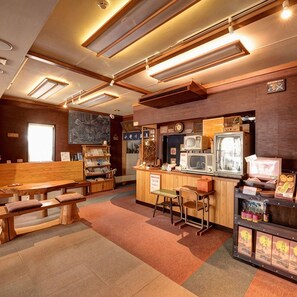 A cozy cafe with wooden furniture, a counter with vintage TVs, and a mural on the wall. - Onogawa Onsen Umeya Ryokan <yamagata> (Yonezawa)