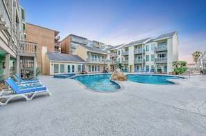 Relax by the central pool surrounded by lounge chairs and a scenic rock feature.