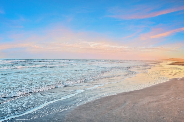 Enjoy a tranquil beach experience with gentle waves lapping onto the shore.