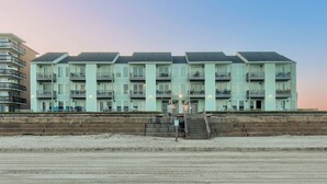 A multi-story hotel with a uniform exterior, located adjacent to a sandy beach. - Beachside Condo | Pool, Hot Tub & Private Balconies (Corpus Christi)