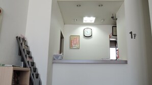 A room with a clock on the wall, a shelf with books, and a small desk area. - Business Hotel Sankai (Obama)
