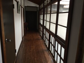 A corridor with wooden flooring, a sliding door with frosted glass panels, and a dark interior. - Kasuga Ryokan (Tokyo)
