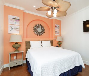 A bedroom with a bed, two nightstands, a ceiling fan, wall art, and a TV. - Dog-Friendly Cottage | Sparkling Pool, Patio & Turf Grass (Corpus Christi)
