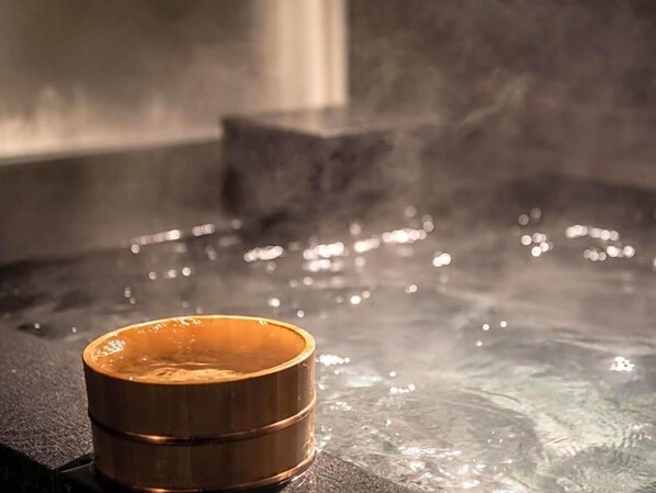 Un jacuzzi con un recipiente de madera en el borde.