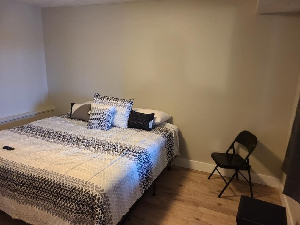 A bedroom with a bed, a chair, and a small table.