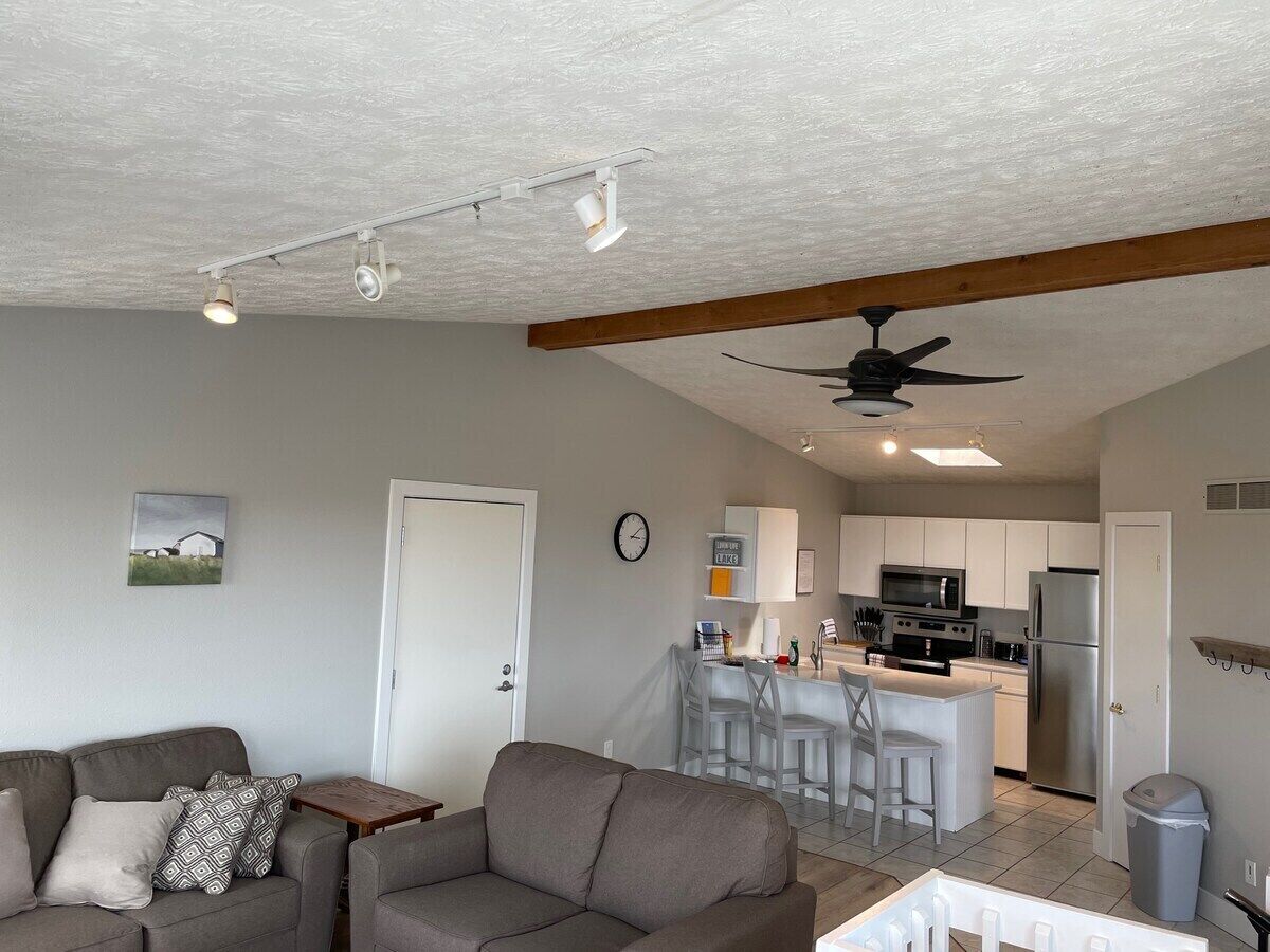 A living room with a sofa, a dining area with a bar, and a kitchen with modern appliances.