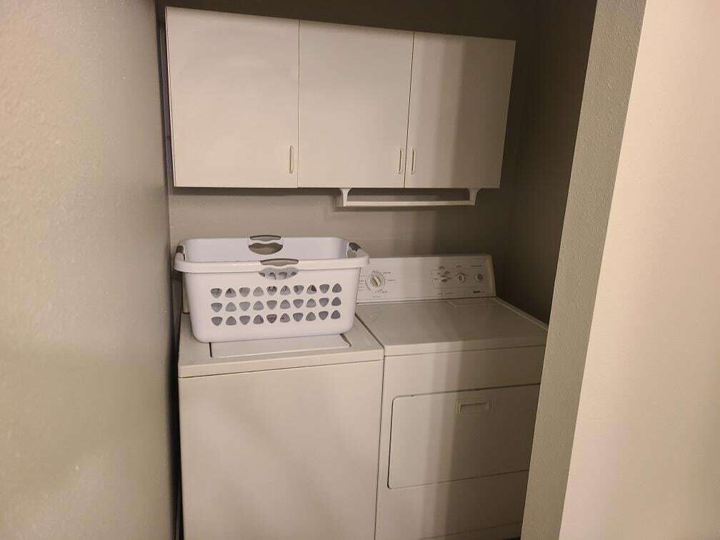 Een kleine wasruimte met een wasmachine en een droogrek.