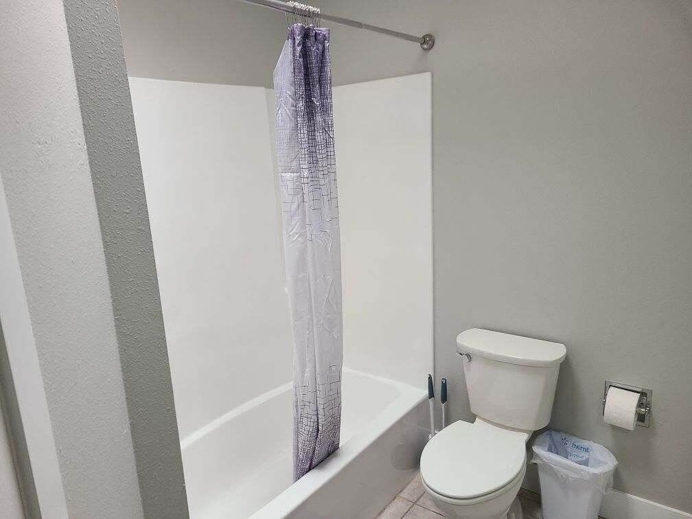 A bathroom with a bathtub, toilet, and a shower curtain.