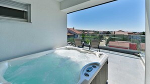 Un balcon avec un jacuzzi, deux chaises et une vue dégagée sur le quartier.