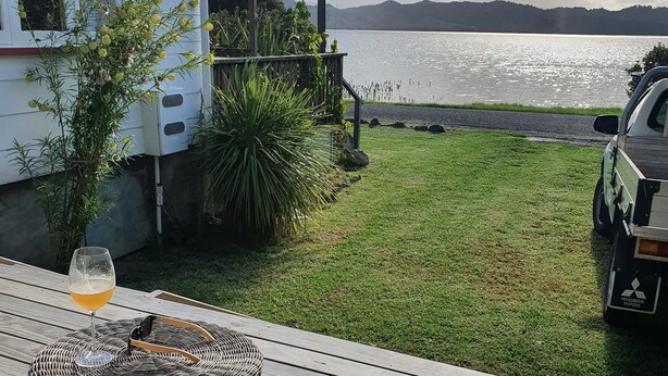 A deck with a table and chairs, overlooking a lake and a camper.