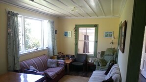 A cozy living room with a sofa, a chair, a small table, and a window with curtains.