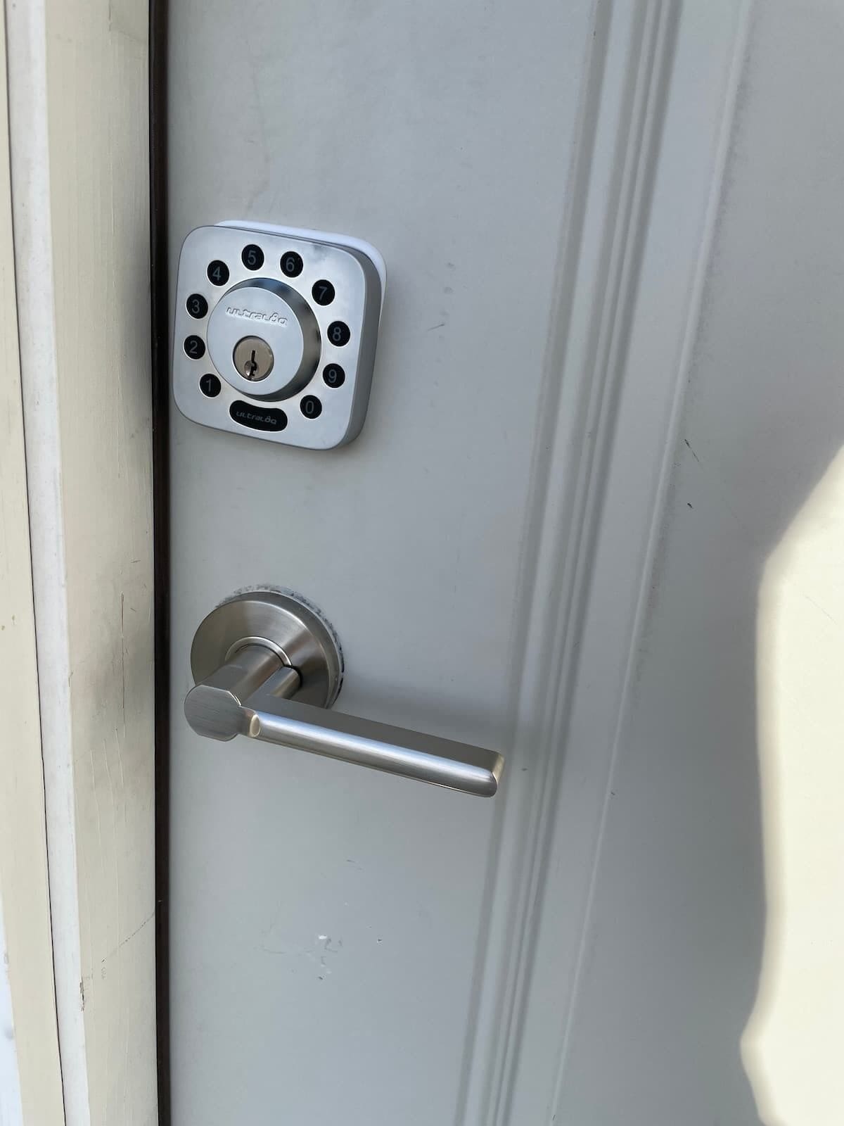 Een deur met een numeriek keypadslot en een hendel.