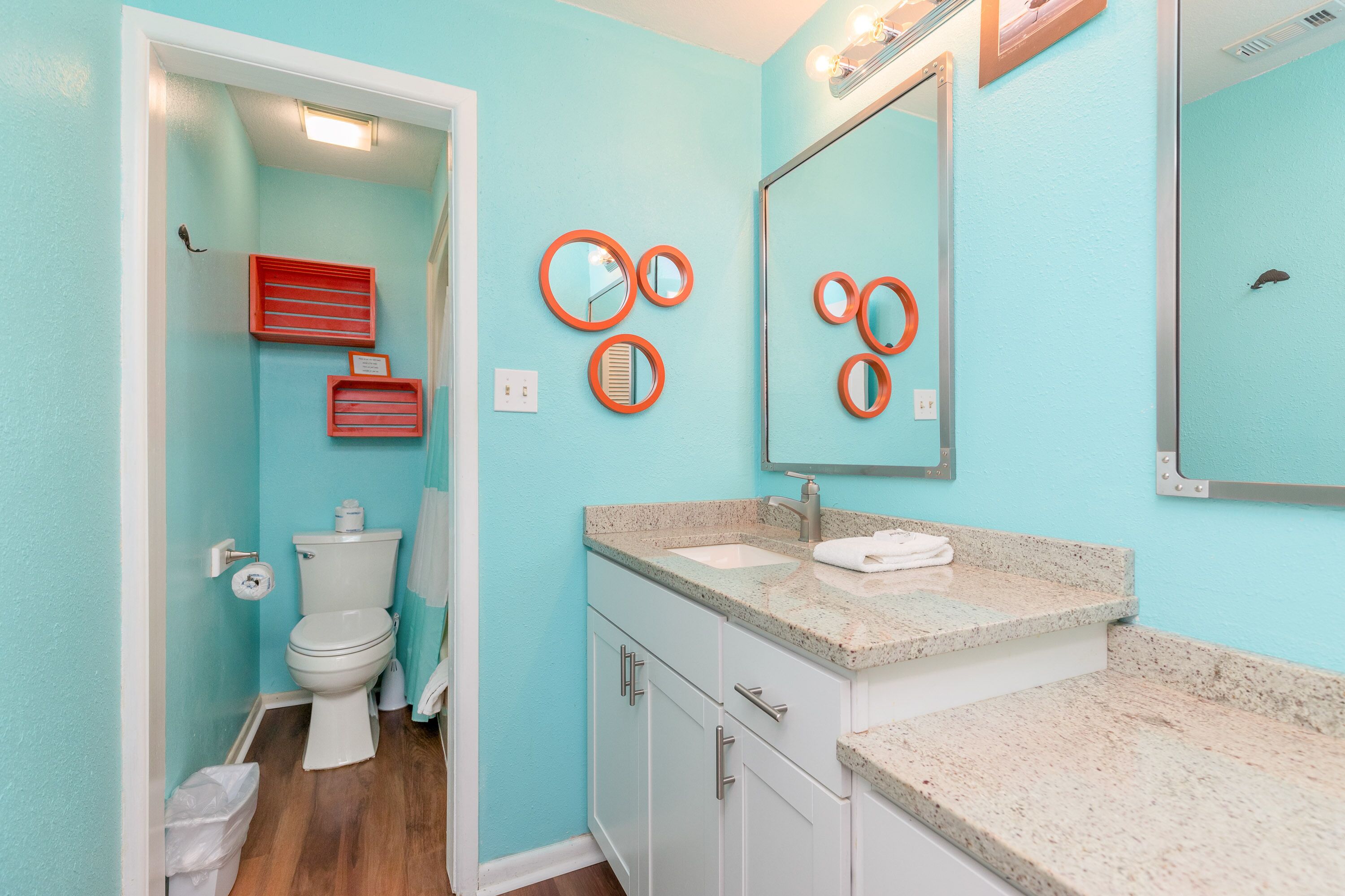 A bathroom with a toilet, sink, and mirrors.