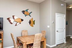 A dining area with a wooden table and wicker chairs, a white door, and wall-mounted fish decorations.