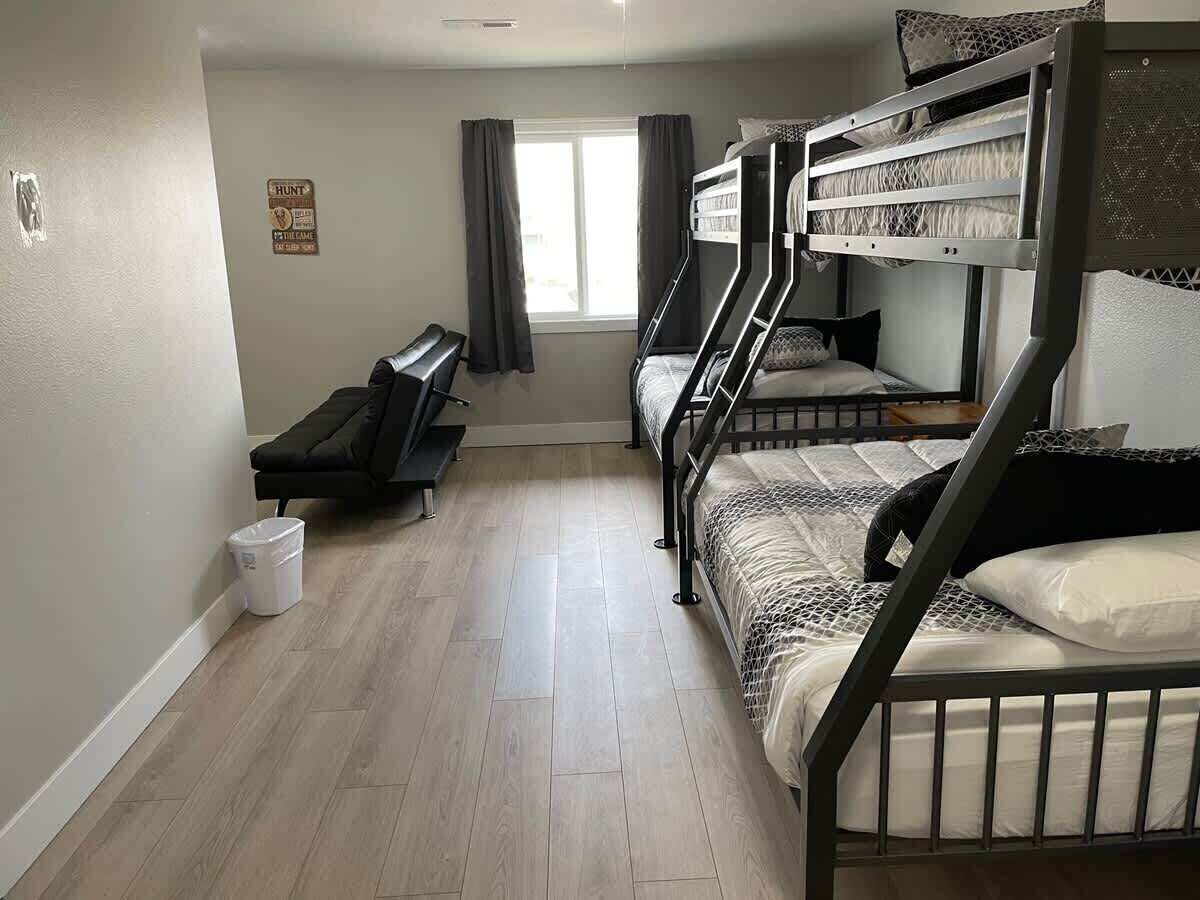 A dormitory room with bunk beds, a desk, and a window with curtains.