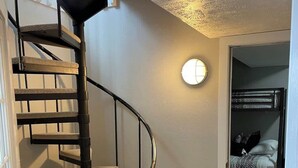Un escalier en colimaçon avec des marches rembourrées menant à un deuxième étage.