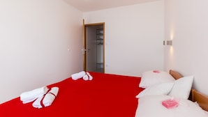 Una habitación de hotel con una colcha roja, almohadas blancas y un cabecero de madera.