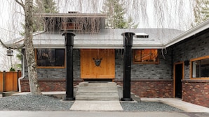 A modern house with a wooden front door, stone facade, and a stone pathway leading to the entrance.
