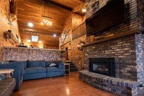 A cozy interior with a brick fireplace, wooden ceiling, and a blue sofa. - AirD&D !!! (Chilliwack)