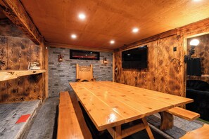 A wooden interior with a large table and benches, stone walls, and a sign reading "DUNGEON MASTER".