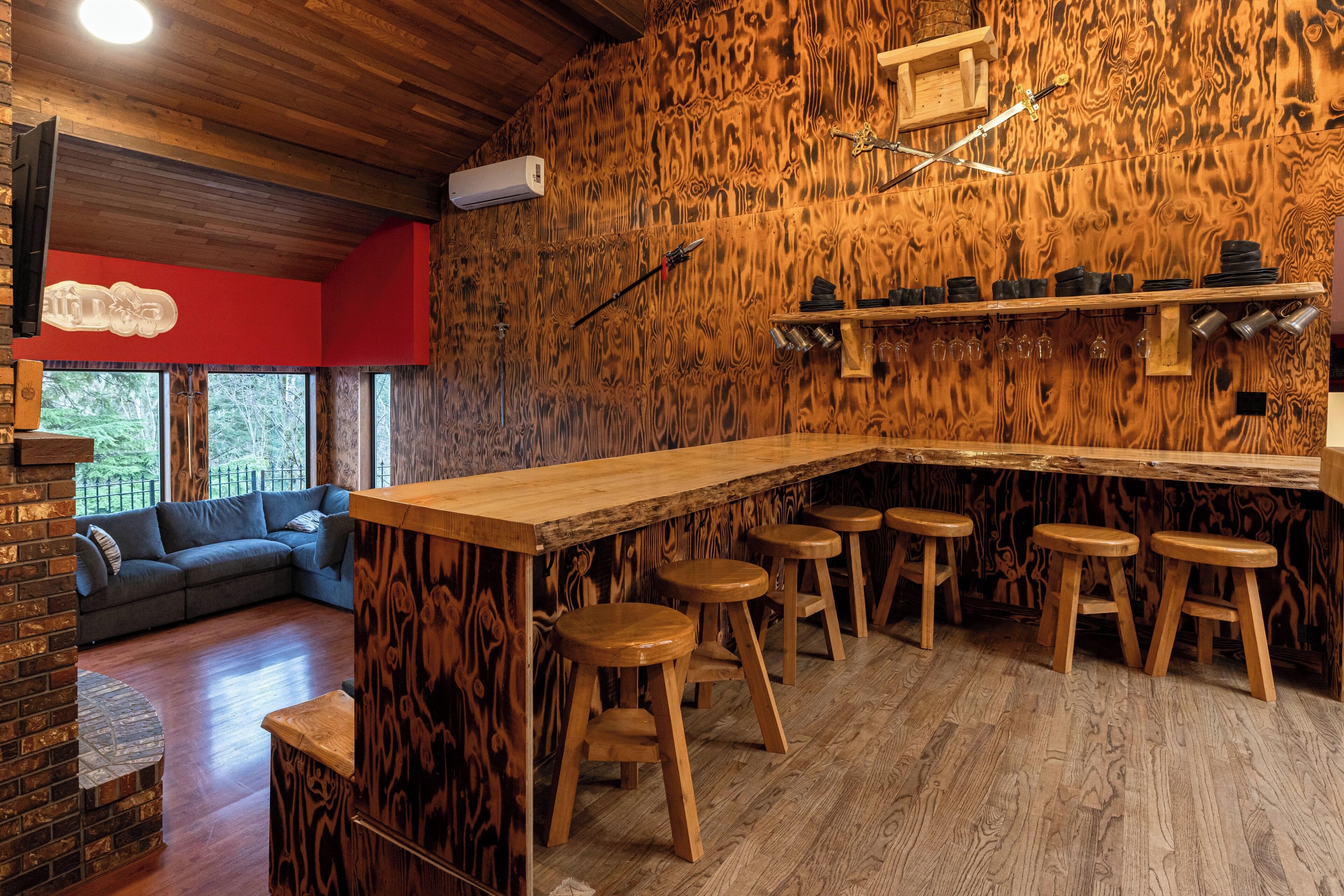 Un espace bar avec des tabourets en bois, un comptoir et des étagères remplies de verres.