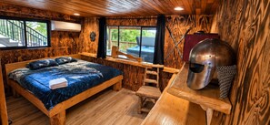 Habitació de temàtica de fusta amb un llit, una banyera d'hidromassatge i un casc d'estil medieval.