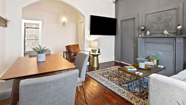 Een eetruimte met een houten tafel en stoelen, een aan de muur bevestigde televisie en een open haard met decoratieve accessoires.