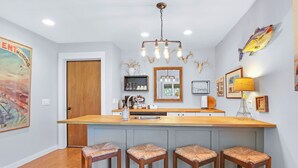 Una cocina moderna con una isla central, taburetes de bar y decoración en la pared.