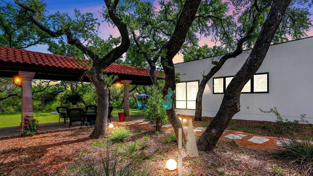 Una casa moderna con patio, rodeada de árboles y un jardín.