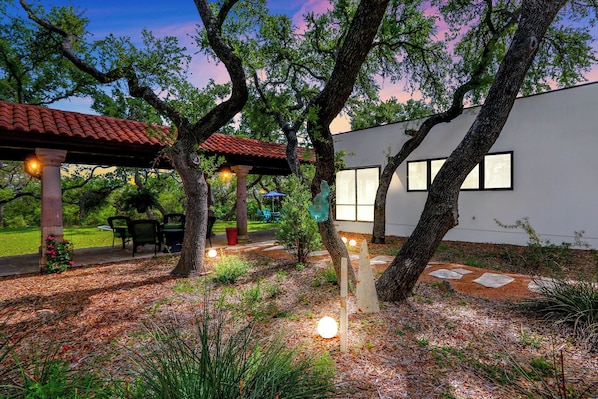 Una casa moderna con patio, rodeada de árboles y un jardín.