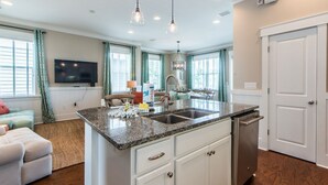 A spacious kitchen with a granite countertop, white cabinetry, and a built-in dishwasher.