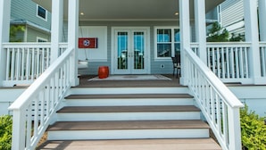 A porch with white railings, a set of wooden steps, and a red mailbox.
