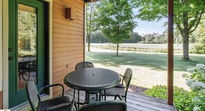 Relax in a serene outdoor space with a deck, table, and chairs, offering a tranquil view of the surrounding grassy field and trees.